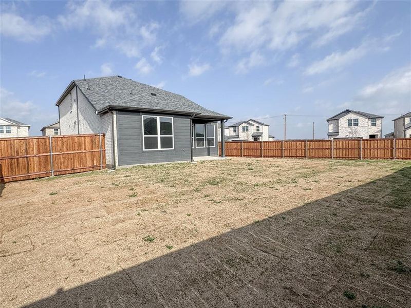 Rear view of property featuring a fenced backyard and roof with shingles