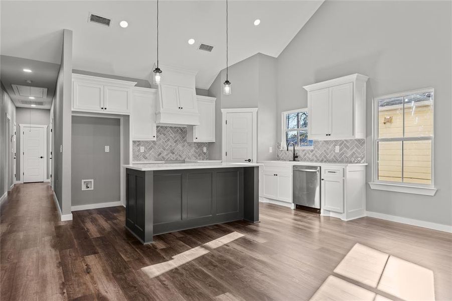 Kitchen featuring white cabinetry, high vaulted ceiling, decorative light fixtures, dishwasher, and light stone countertops