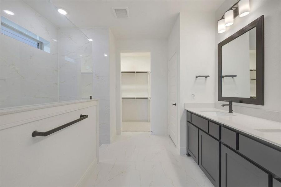 Spacious bathroom featuring a double vanity with stone countertops, a large framed mirror, and matte black fixtures