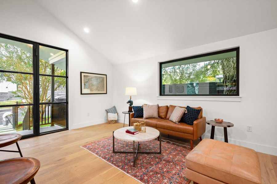 Living room with vaulted ceiling, light wood-style floors, and recessed lighting