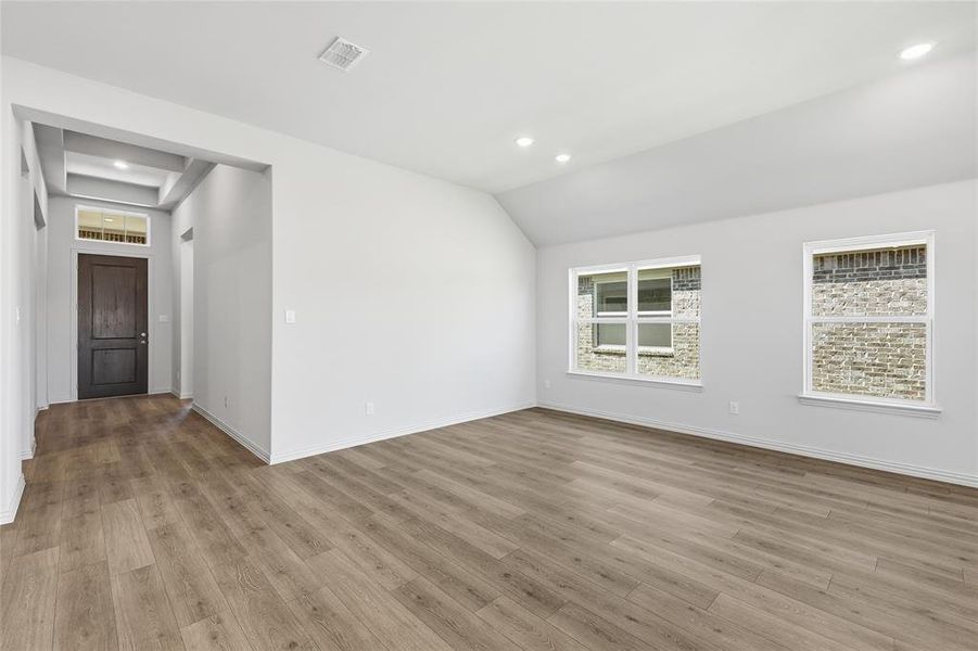Unfurnished room featuring light wood-style flooring, recessed lighting, and lofted ceiling