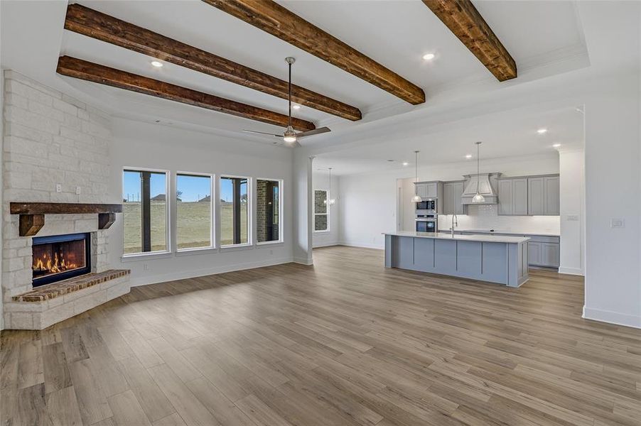 Unfurnished living room with recessed lighting, a ceiling fan, a stone fireplace, beamed ceiling, and dark wood-style floors