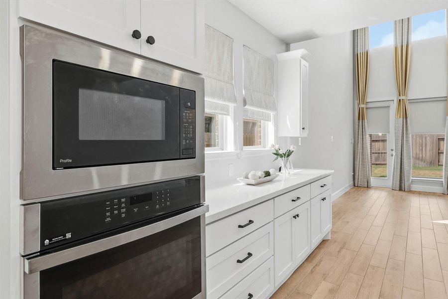 Premium built-in stainless steel appliances, extensive cabinetry, and a spacious serving area combine to create a kitchen that's as functional as it is beautiful. Large windows and soaring ceilings continue the home's bright, airy ambiance throughout the adjoining dining and living spaces.