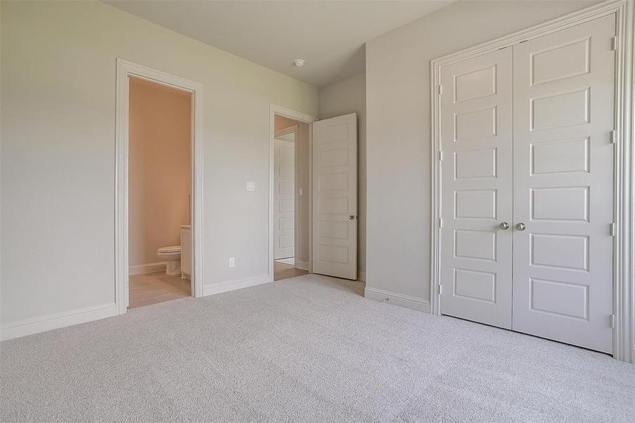 Unfurnished bedroom with light carpet, a closet, and connected bathroom