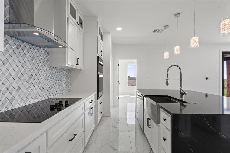 Kitchen with white cabinetry, sink, hanging light fixtures, wall chimney exhaust hood, and black electric cooktop