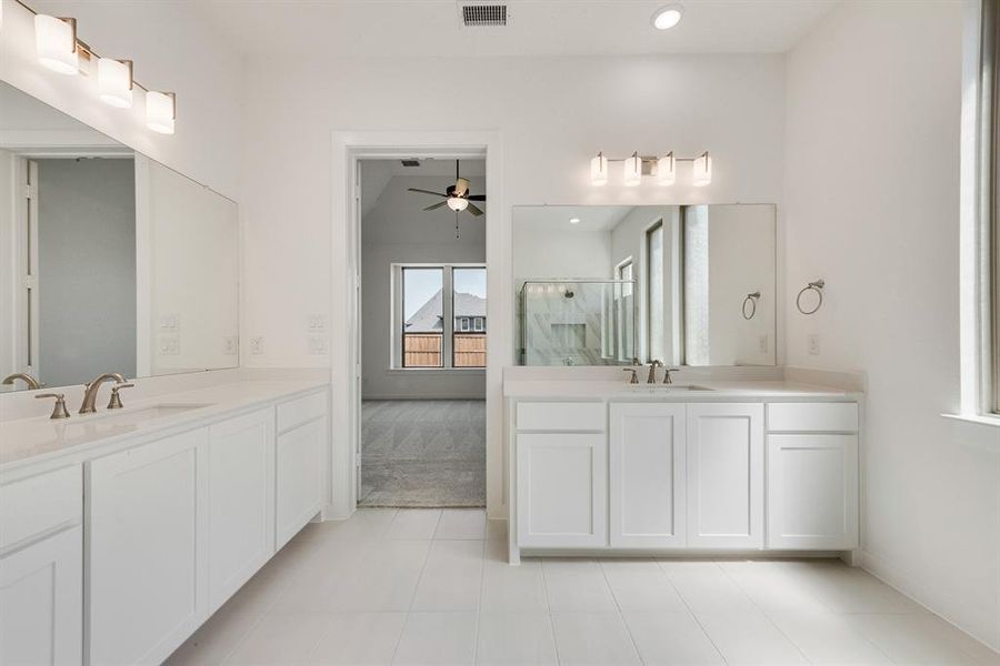 Bathroom with a stall shower, two vanities, light tile patterned floors, a ceiling fan, and recessed lighting Bathroom with a stall shower, two vanities, light tile patterned floors, a ceiling fan, and recessed lighting