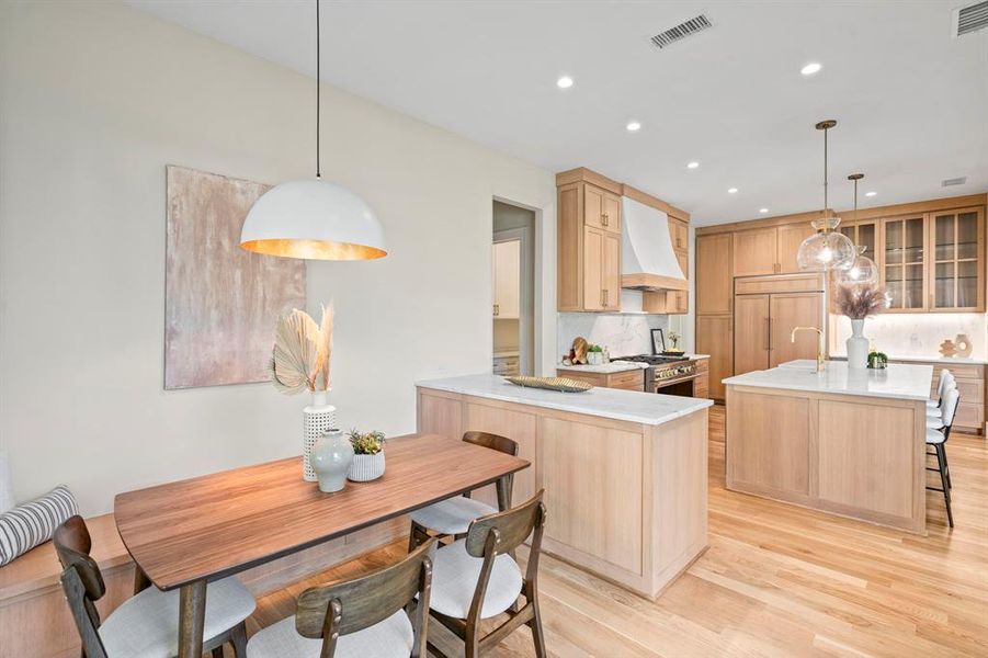 Kitchen featuring high quality appliances, decorative backsplash, light hardwood / wood-style flooring, and custom range hood