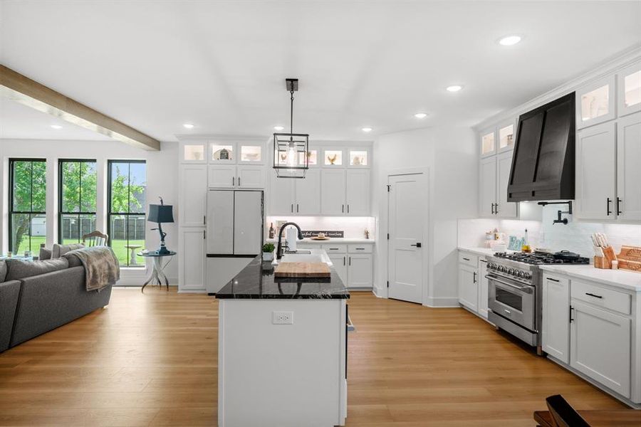 Kitchen featuring high end stove, range hood, recessed lighting, a sink, and light wood-style flooring Kitchen featuring high end stove, range hood, recessed lighting, a sink, and light wood-style flooring