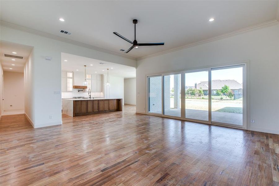 Unfurnished living room featuring ornamental molding, light hardwood / wood-style floors, and ceiling fan