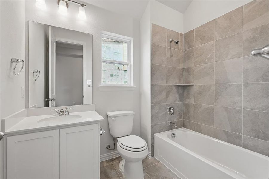 Bathroom with vanity, bathtub / shower combination, and light tile patterned floors