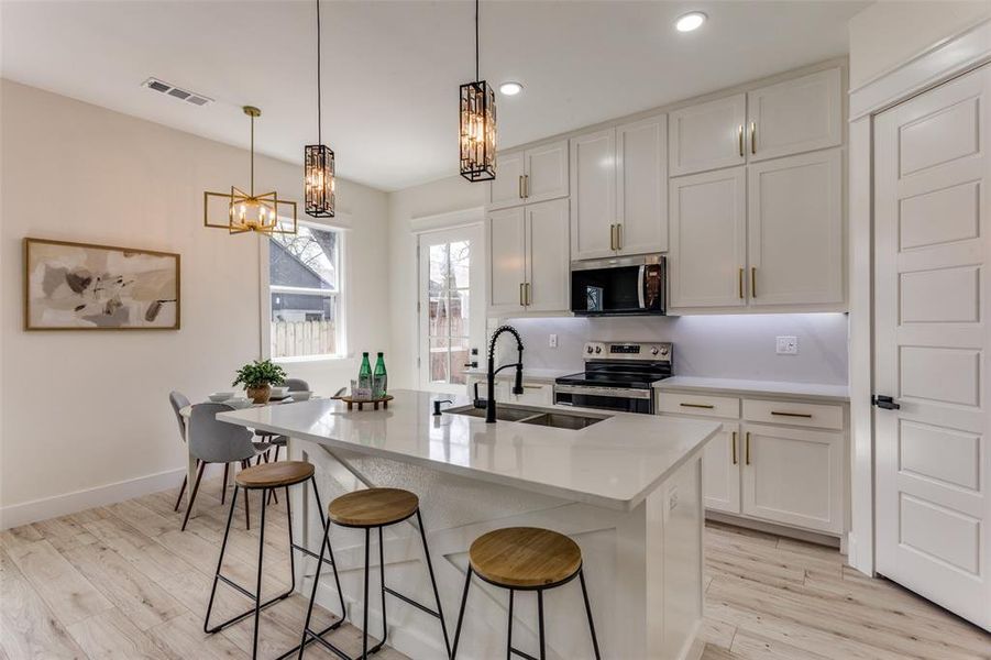 Kitchen featuring visible vents, a notable chandelier, light wood-style flooring, appliances with stainless steel finishes, and light countertops