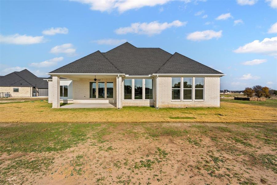 Back of house with ceiling fan, a yard, and a patio