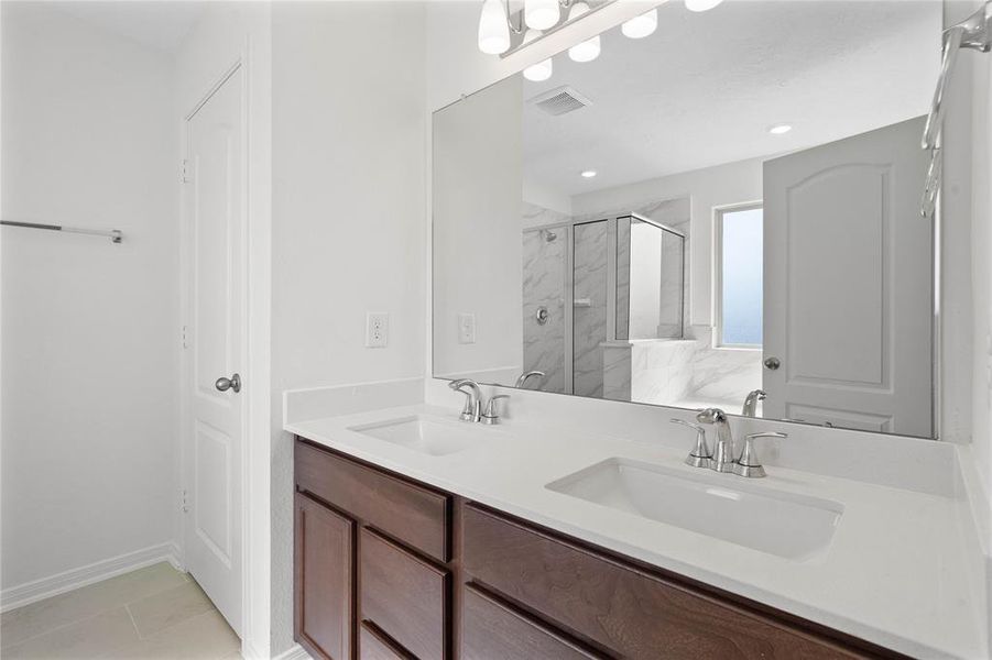 This large primary bath is spacious enough to share! With separate vanities, plentiful cabinet and counter space, you are sure to have private area while sharing this bathroom!