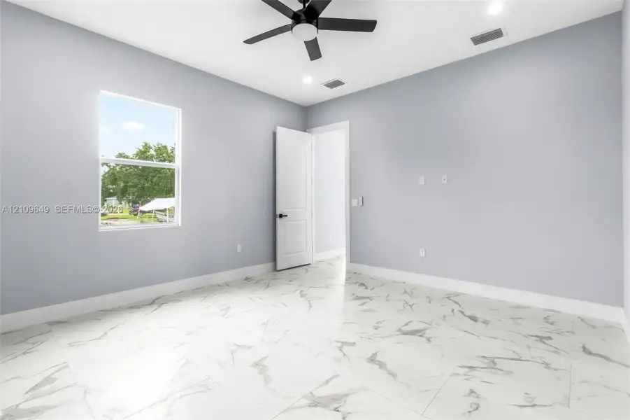 Neutral-toned room featuring large-format stone-patterned tile flooring, a multi-speed ceiling fan, recessed lighting, and a single-hung window