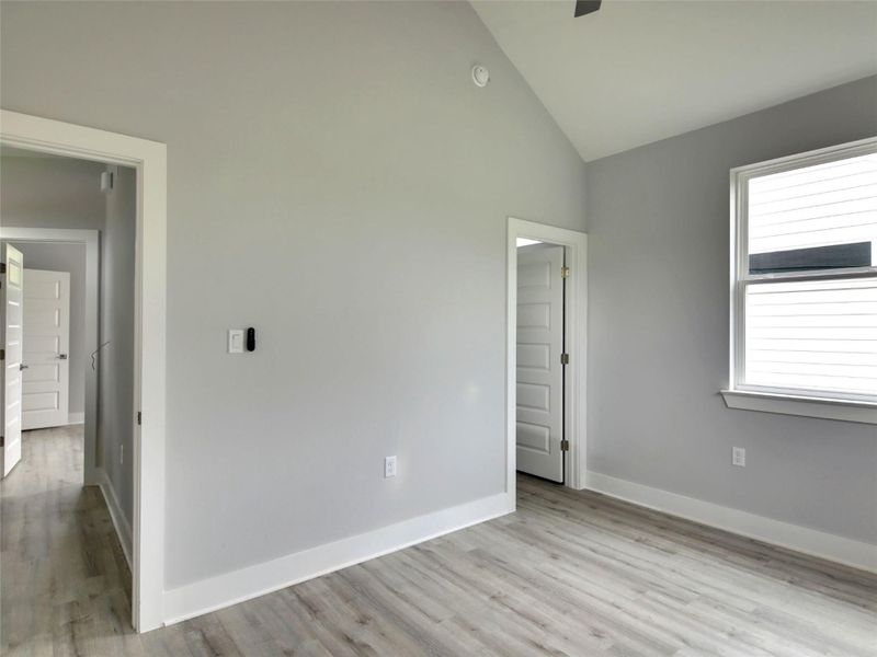Unfurnished bedroom featuring light wood finished floors, a ceiling fan, and high vaulted ceiling