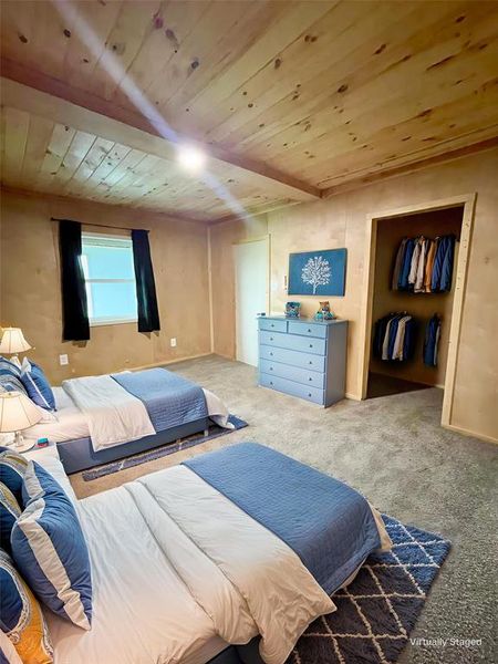 Bedroom with carpet floors and a wood ceiling with exposed beams