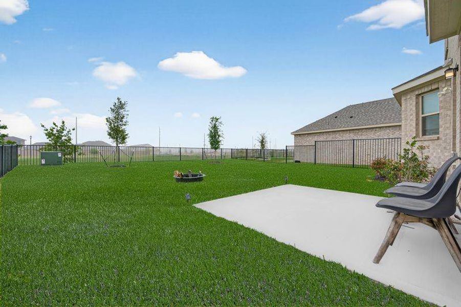 Extended concrete patio opens to a wide, fenced backyard with no rear neighbors.