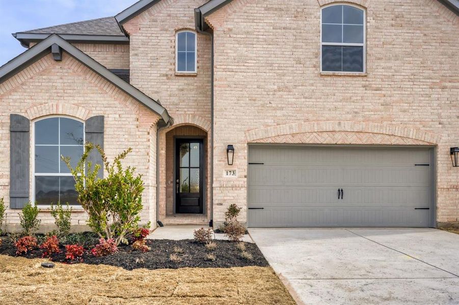 French country style house with brick siding, concrete driveway, a garage, and roof with shingles
