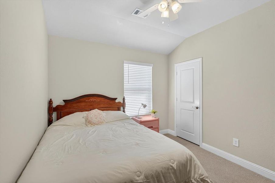 Carpeted room featuring a vaulted ceiling and a ceiling fan with integrated lighting Carpeted room featuring a vaulted ceiling and a ceiling fan with integrated lighting
