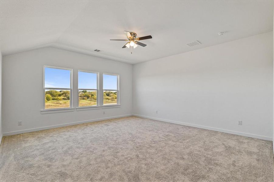 Carpeted spare room featuring ceiling fan and vaulted ceiling Carpeted spare room featuring ceiling fan and vaulted ceiling