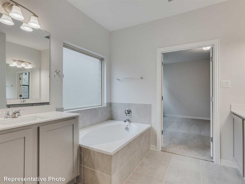 Bathroom featuring vanity, light tile patterned floors, a garden tub, and light carpet