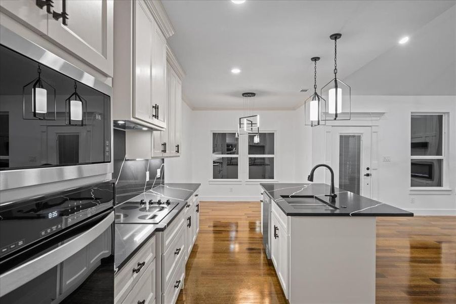 Kitchen featuring stainless steel appliances, dark counters, tasteful backsplash, off-white cabinets, and ornamental molding Kitchen featuring stainless steel appliances, dark counters, tasteful backsplash, off-white cabinets, and ornamental molding