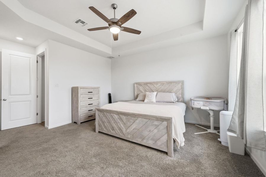 Carpeted bedroom featuring a tray ceiling, ceiling fan, and recessed lighting