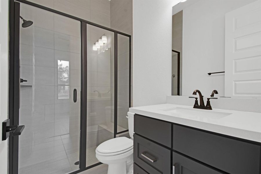 Full ensuite bathroom in Bedroom #2 with vanity, a stall shower with bench seat, and light tile patterned floors