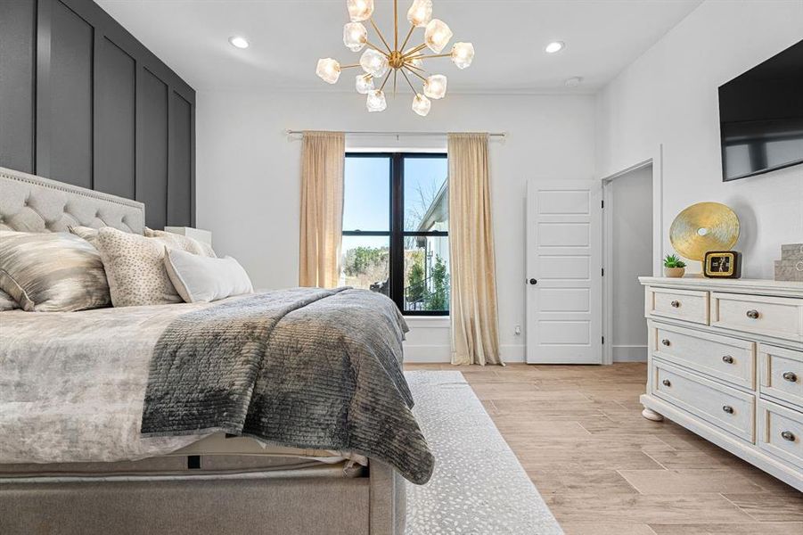 Bedroom featuring light wood-type flooring, baseboards, recessed lighting, and a notable chandelier Bedroom featuring light wood-type flooring, baseboards, recessed lighting, and a notable chandelier