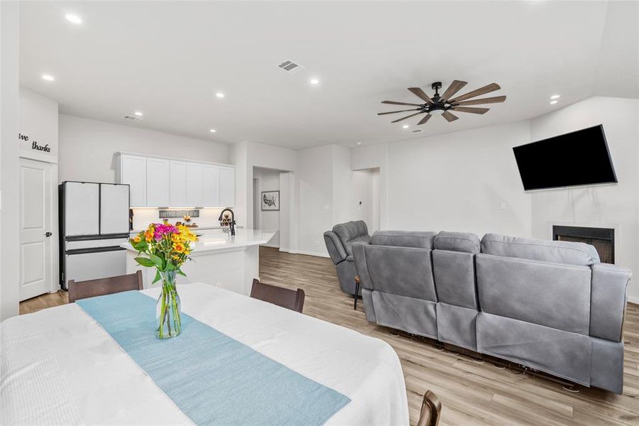 This is an open-concept living space with a seamlessly flowing kitchen, featuring white cabinetry and contemporary appliances. The area is well-lit with recessed lighting and includes a comfortable living room. The room's clean lines and neutral color palette provide a fresh canvas for personalization.