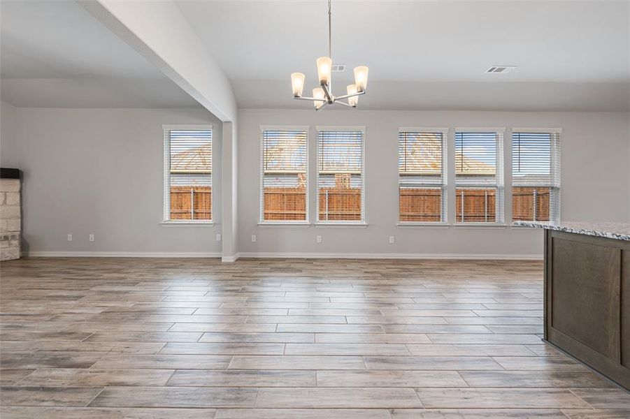 Unfurnished dining area featuring healthy amount of natural light, wood finish floors, and a chandelier Unfurnished dining area featuring healthy amount of natural light, wood finish floors, and a chandelier