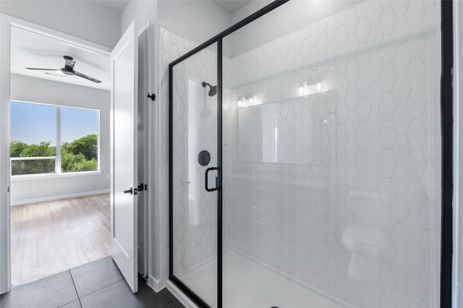 Bathroom with a ceiling fan, a stall shower, and tile patterned floors
