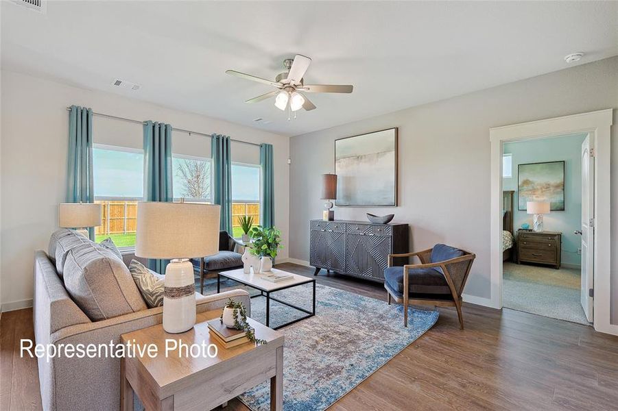 Spacious living area featuring wood-finish flooring, light grey wall paint, and a ceiling fan