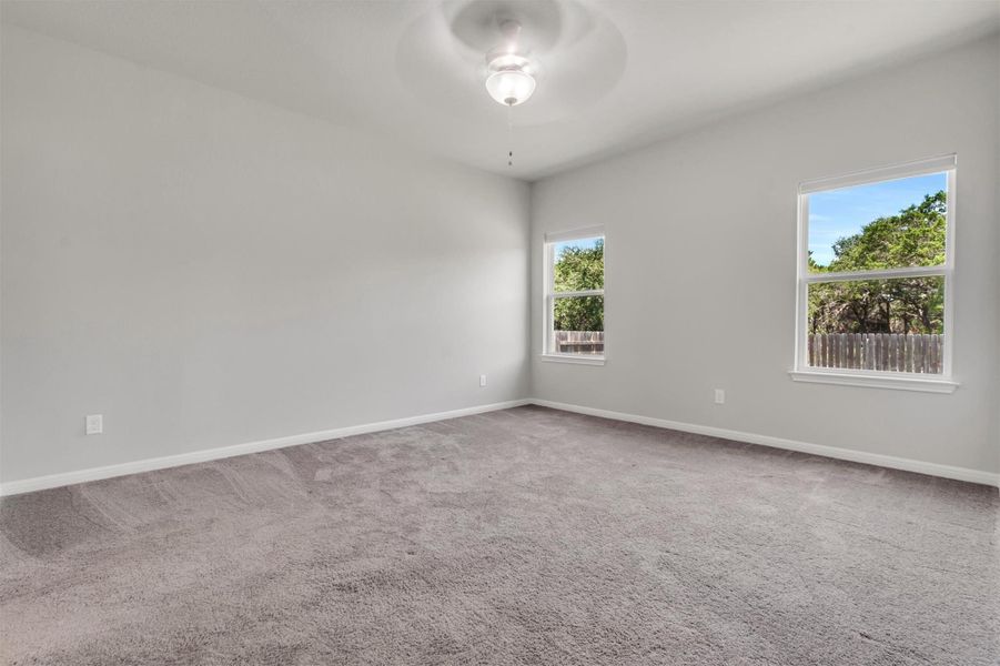 A well-lit bedroom provides comfort with soft carpet and a serene view of surrounding trees.