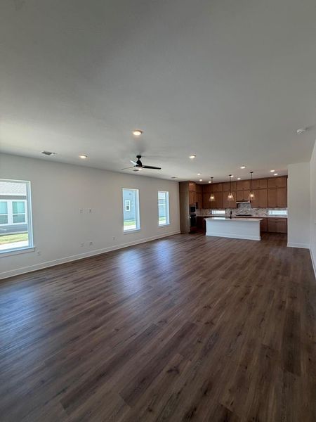 An open-concept layout unites the living area and kitchen, featuring rich wood flooring and abundant natural light.