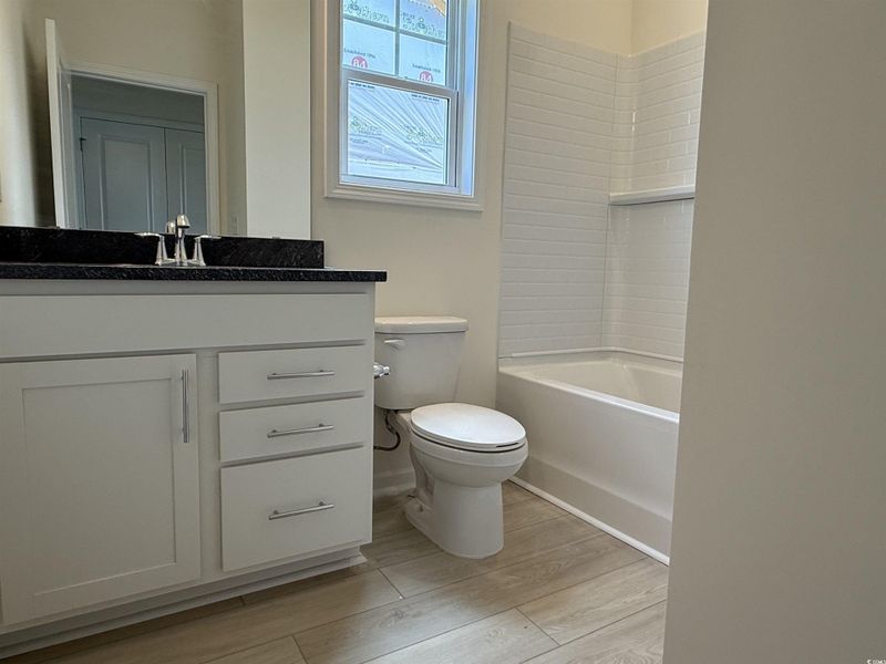 Full bath with wood finished floors, vanity, and washtub / shower combination Full bath with wood finished floors, vanity, and washtub / shower combination