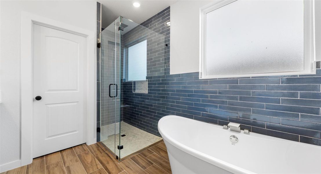 Full bathroom featuring a shower stall, a freestanding tub, wood tiled floors, and tile walls
