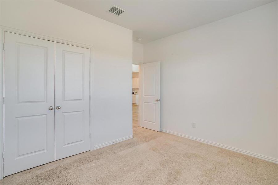 Unfurnished bedroom with light carpet and a closet