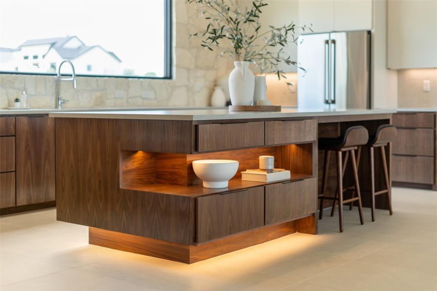 Kitchen with modern cabinets, high end refrigerator, backsplash, light countertops, and a breakfast bar