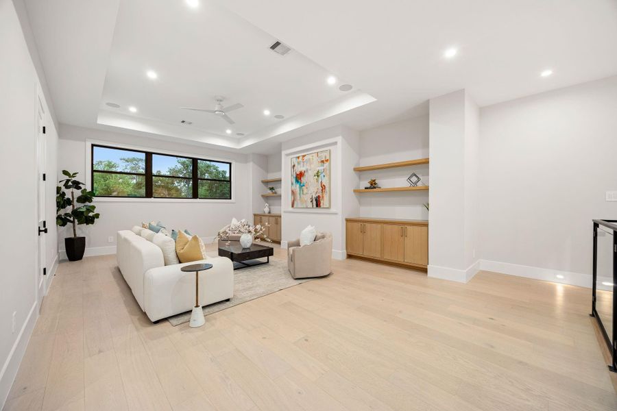 A beautifully designed living space showcasing a seamless blend of comfort and style, with soft neutral tones and thoughtfully curated finishes. Built-in cabinetry and floating shelves provide both function and visual interest. The highlight of this room is the custom built-in wall with integrated storage and display shelving, creating a refined focal point perfect for showcasing art and décor.