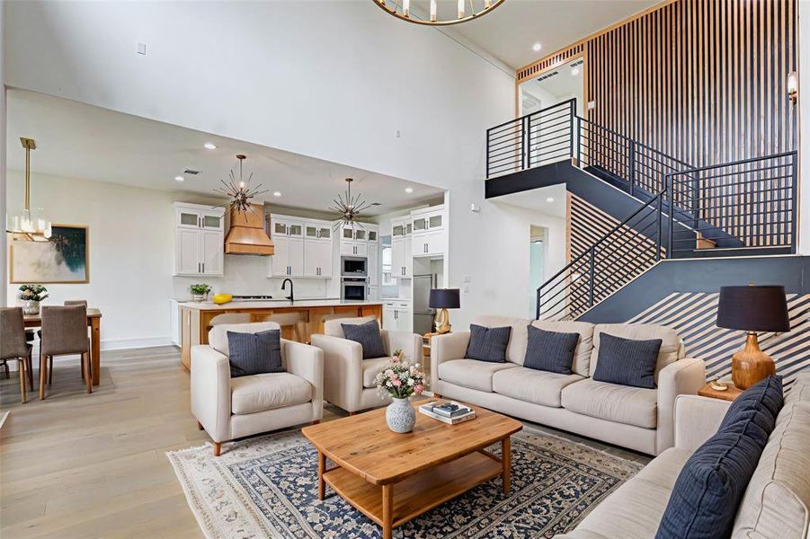Living room with a chandelier, recessed lighting, stairs, a towering ceiling, and light wood finished floors