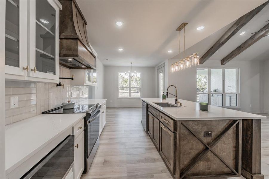 Kitchen featuring dark brown cabinets, stainless steel appliances, white cabinets, premium range hood, and beamed ceiling
