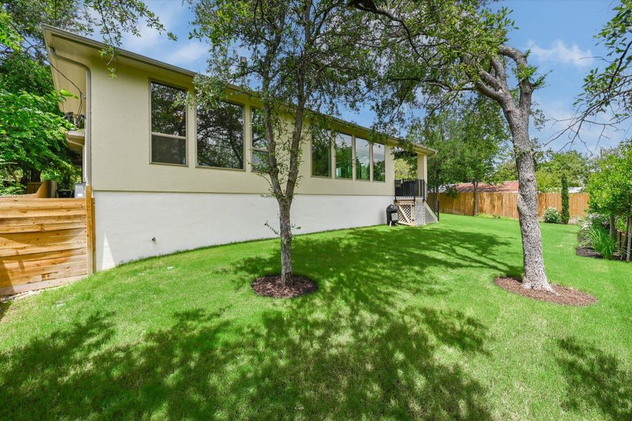 A verdant backyard with mature trees complements the bright, modern architecture.