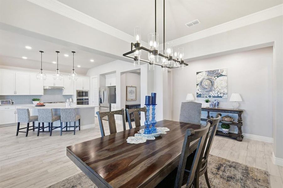Dining room featuring ornamental molding, light wood-type flooring, recessed lighting, and a chandelier