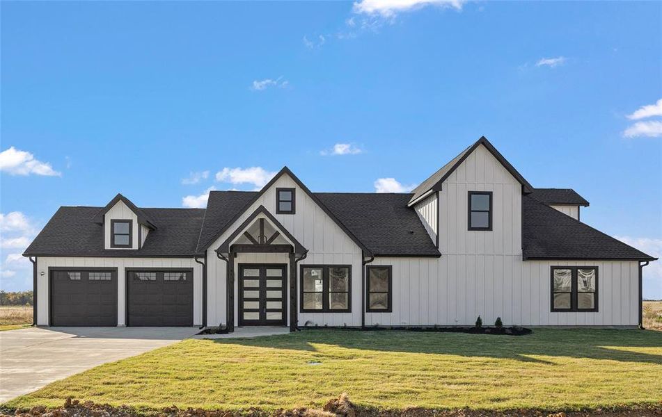 Modern farmhouse style home featuring a front yard and a garage