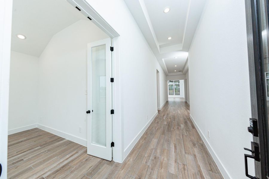An inviting entrance opens up to an open-concept layout, seamlessly connecting the entry to the living areas with durable wood look tile flooring and striking architectural details.