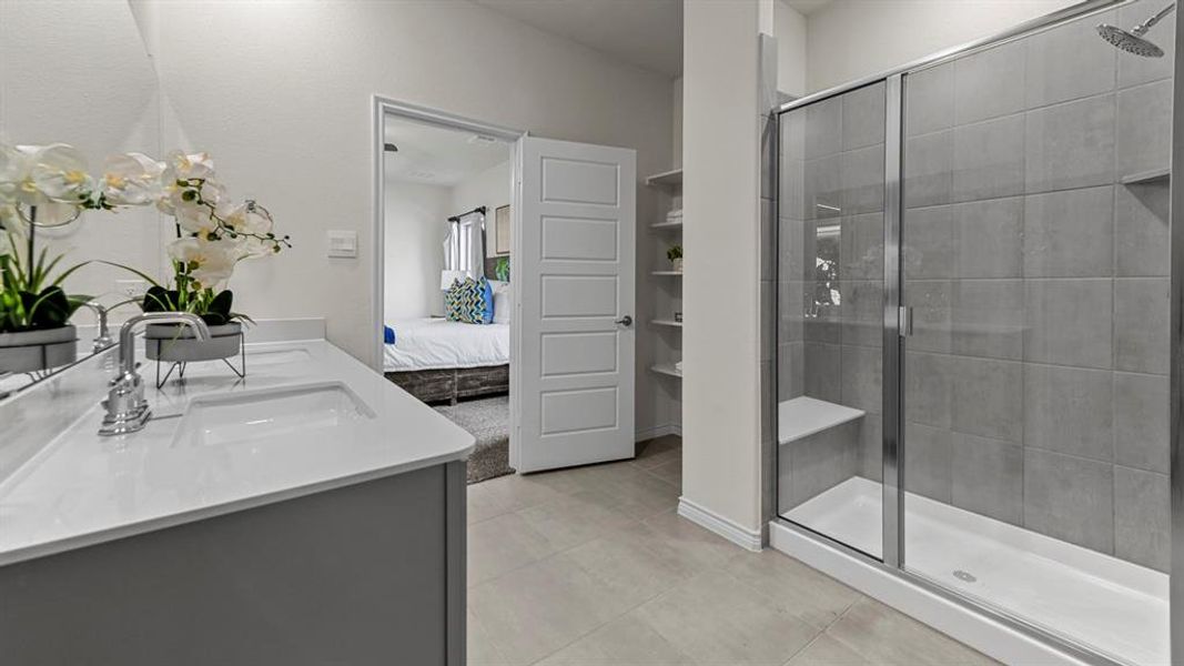 Double vanity with undermount sinks, a spacious walk-in shower with a built-in bench, and a tiled shower surround