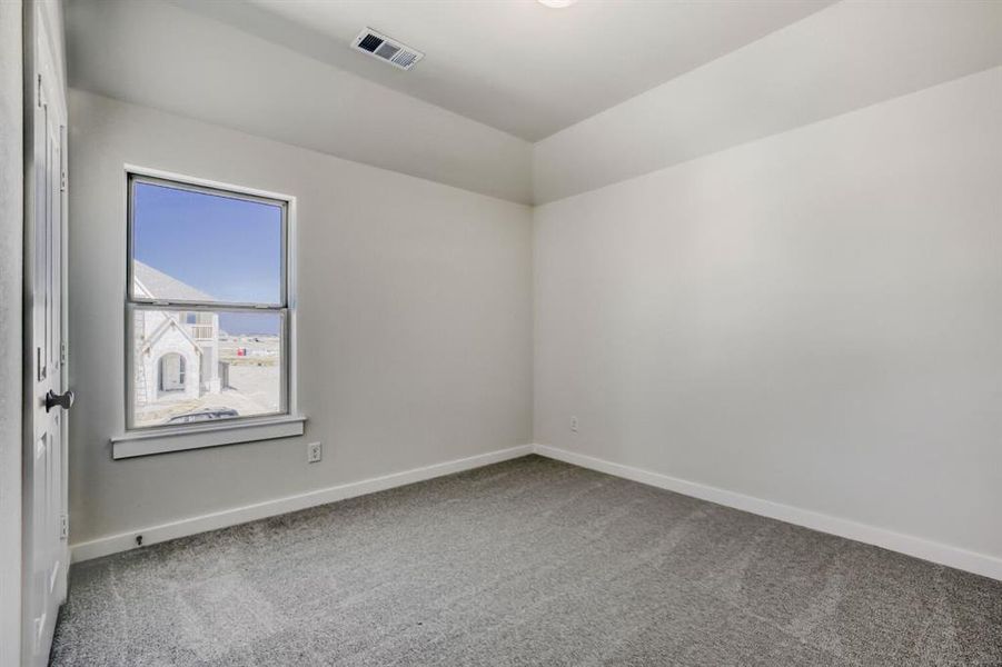 Empty room featuring light carpet and lofted ceiling