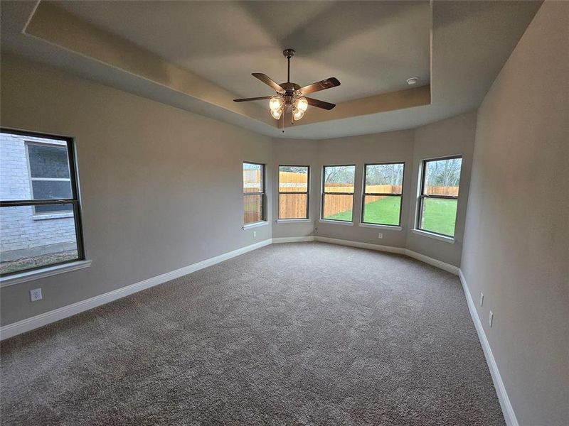 Master bedroom offers bay window, tray ceiling , and a ceiling fan