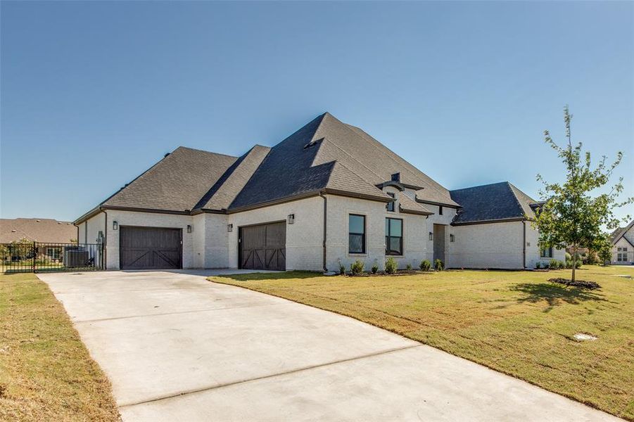 French country style house featuring cooling unit, a garage, and a front lawn